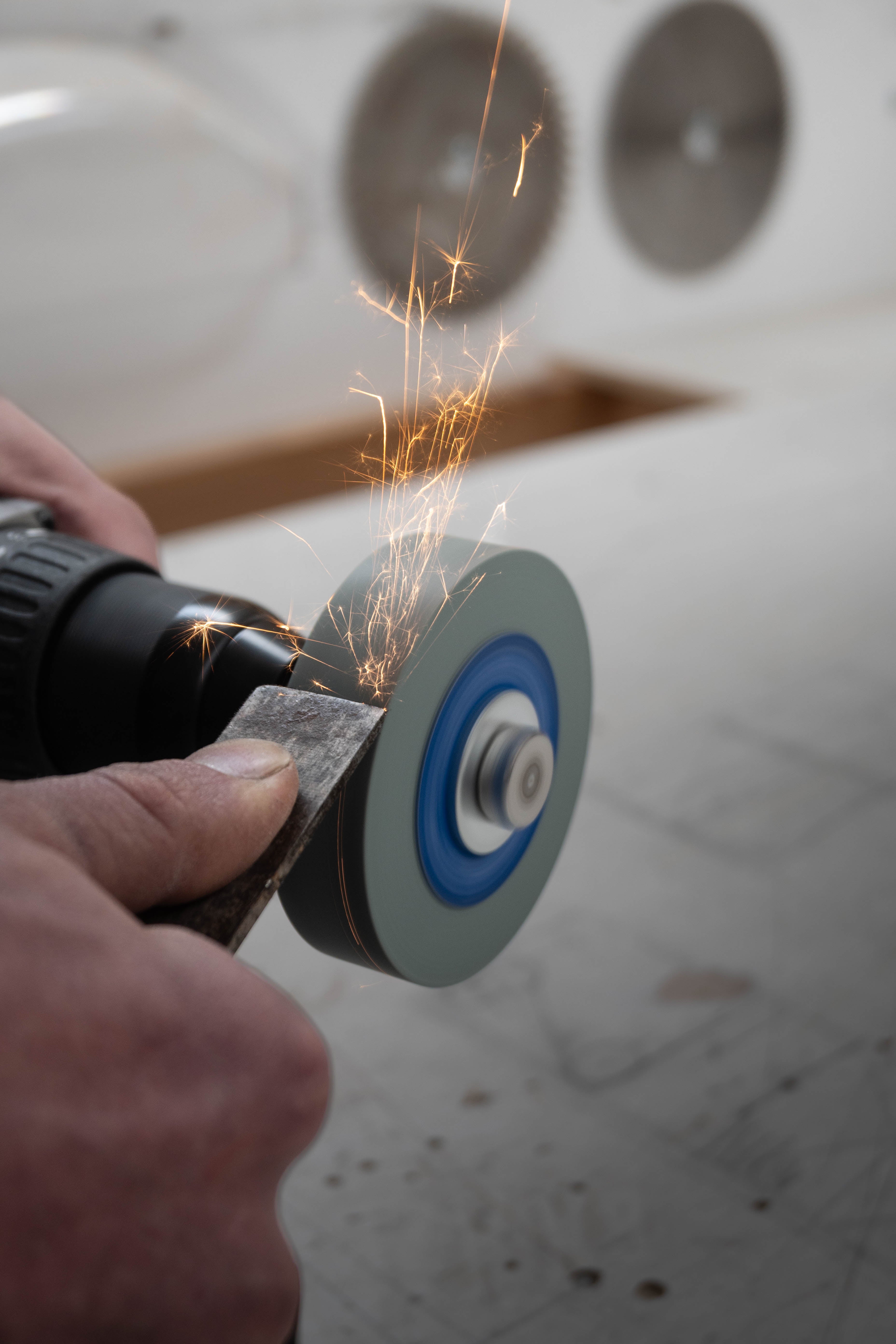 Chisel being sharpened using SharpStone 1.0 grinding disc mounted on a cordless drill, sparks flying